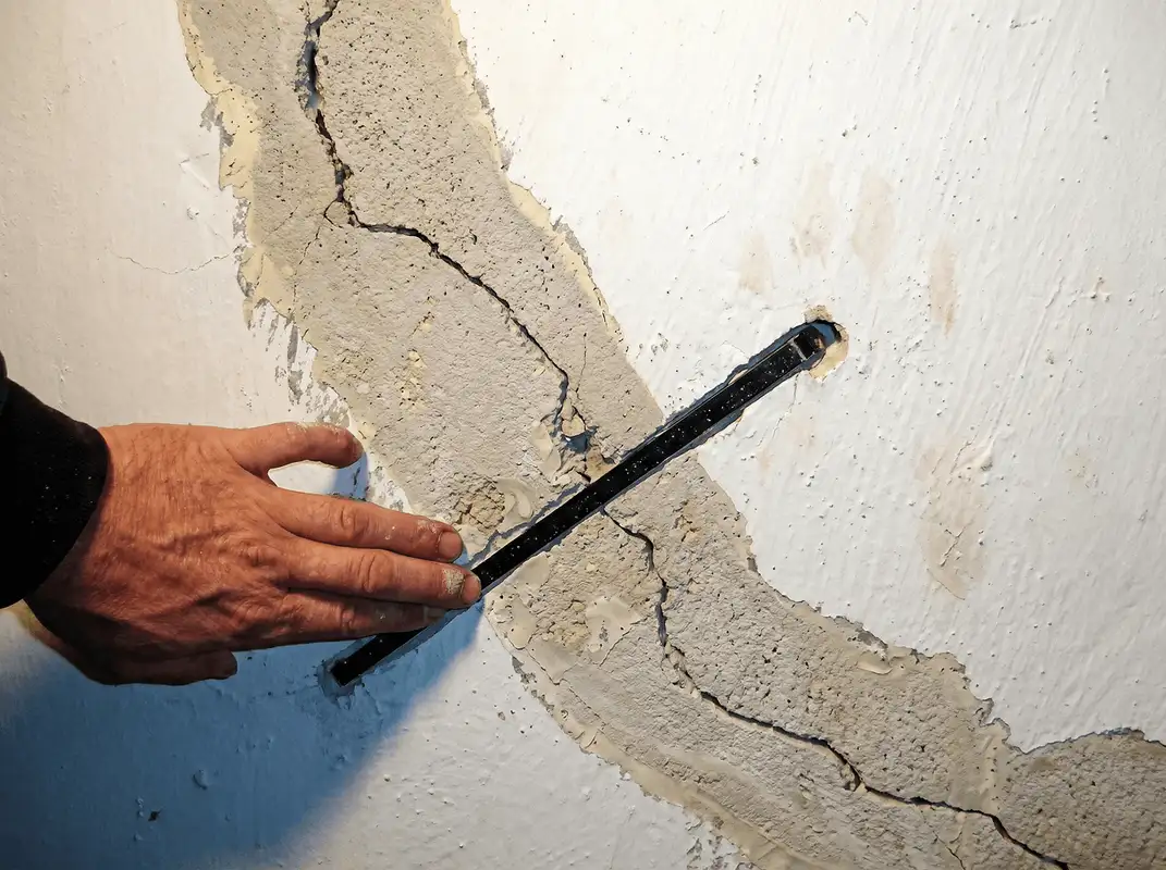 A wall with a large crack is being inspected by a professional in Anchorage, AK